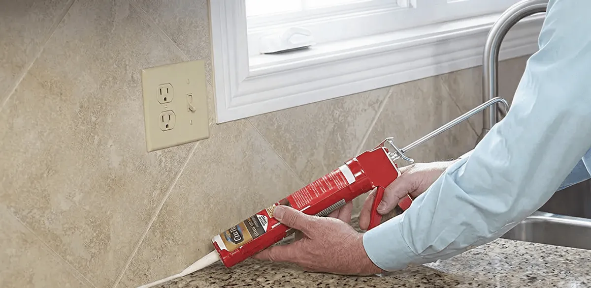 Handyman applying caulk along a kitchen backsplash and countertop seam in Erie, PA
