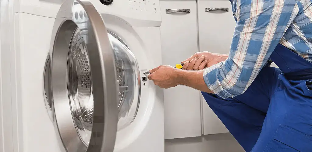 Handyman repairing a clothes dryer and checking electrical connections in Erie, PA
