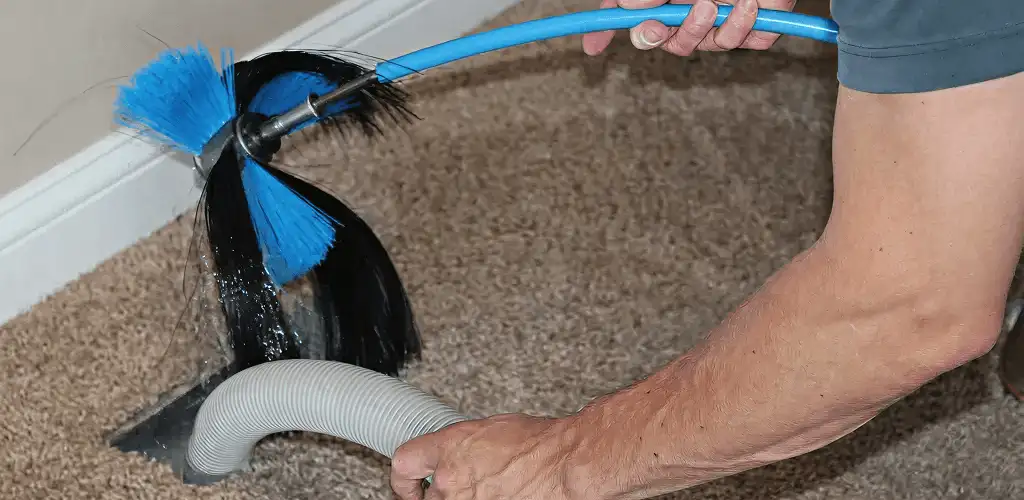 Dryer vent cleaning technician brushing lint from a vent line in Erie, PA