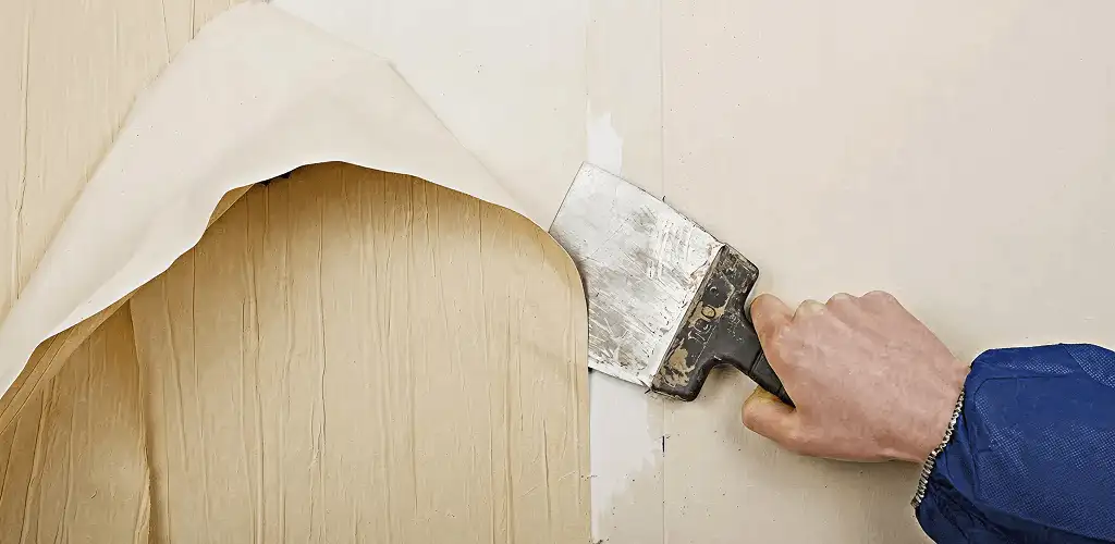 Handyman removing wallpaper with a scraper for wall preparation in Erie, PA