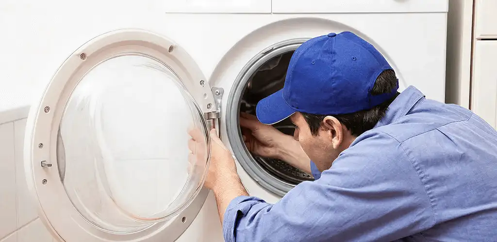 Washing machine repair handyman inspecting a front-load washer drum in Erie, PA