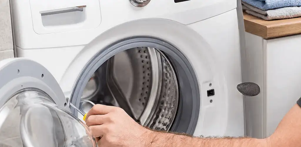Handyman repairing a front-load washing machine and inspecting the drum in Erie, PA