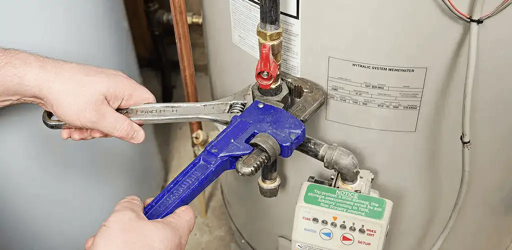 Water heater repair technician tightening the shutoff valve and supply line in Erie, PA